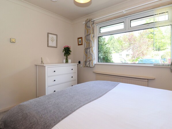 Un dormitorio con cama, cómoda, ventana con persianas y radiador.