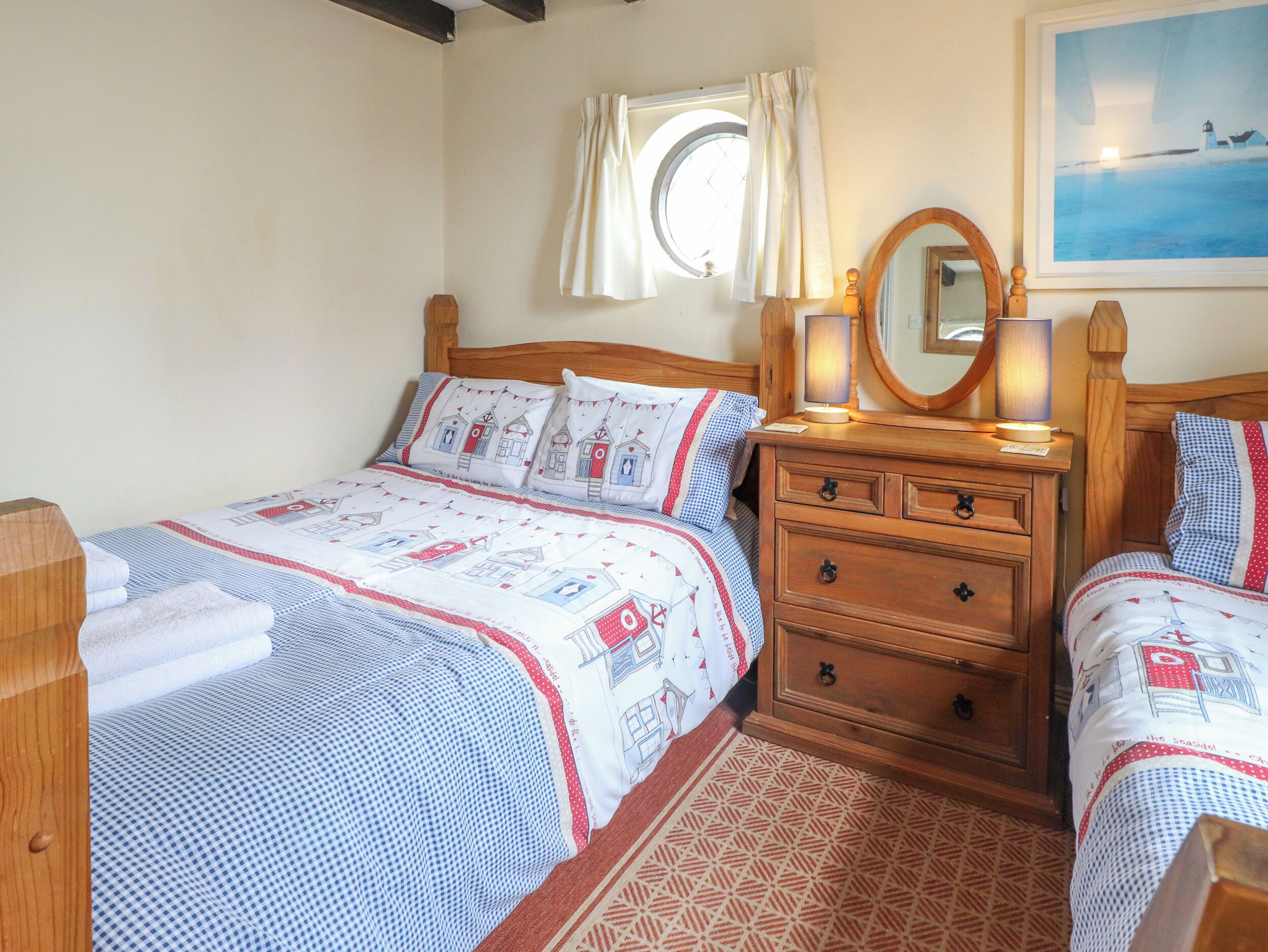 A bedroom with a bed, bedside table, mirror, and a window with curtains.
