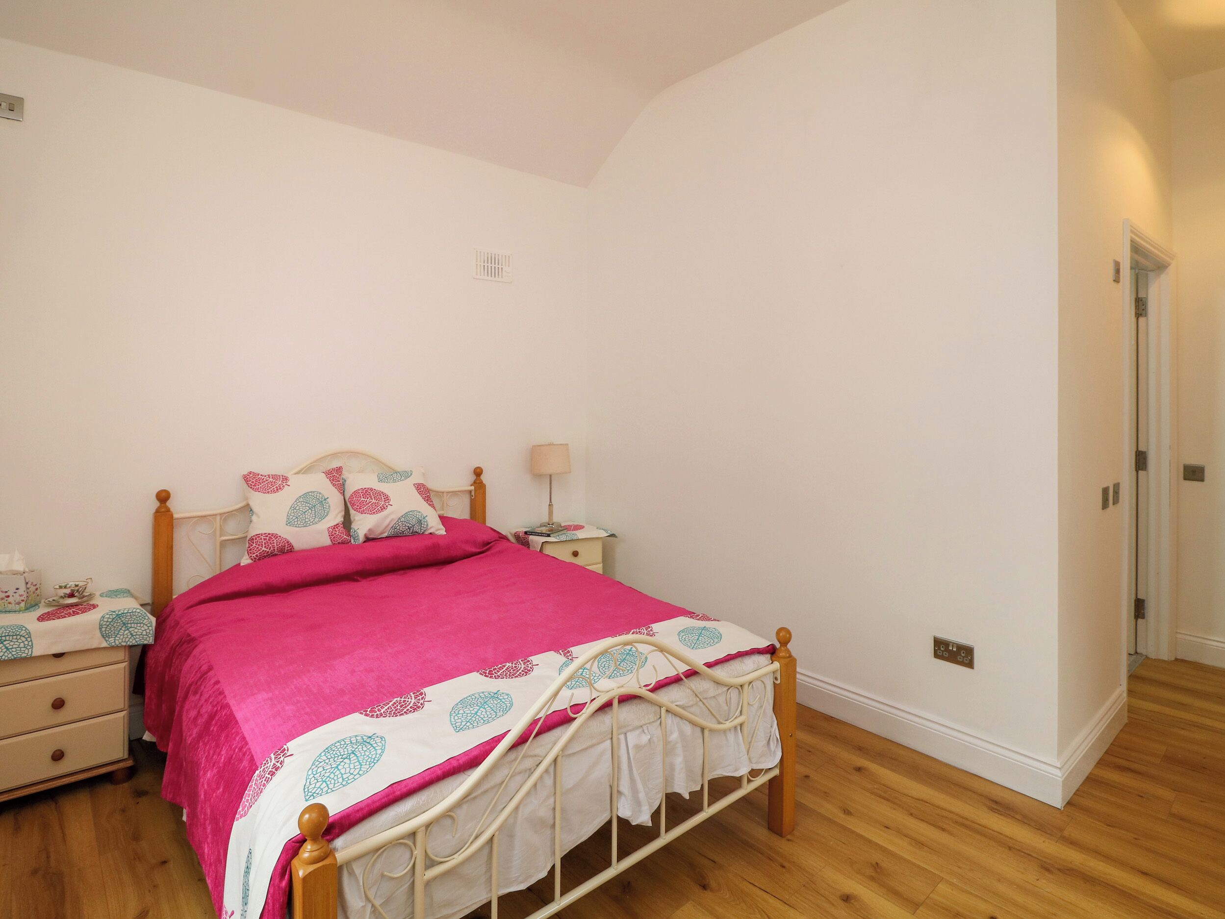 A bedroom with a bed, bedside tables, a nightstand, and a door.