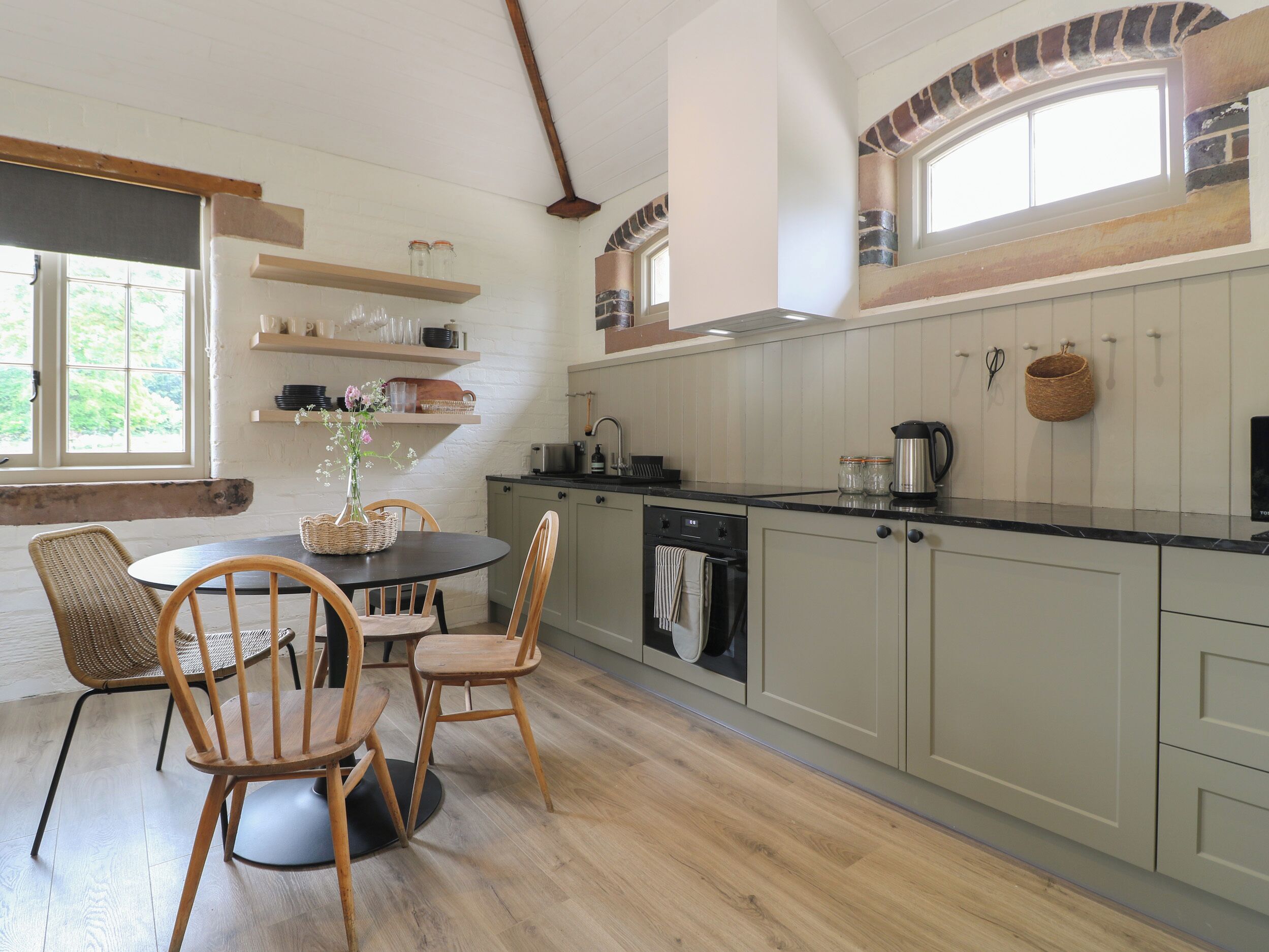 A kitchen with wooden cabinets, a black countertop, and a dining area with wicker chairs.