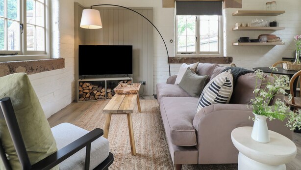 Un salon confortable avec un téléviseur à écran plat, un canapé, un fauteuil, une petite table et une lampe.