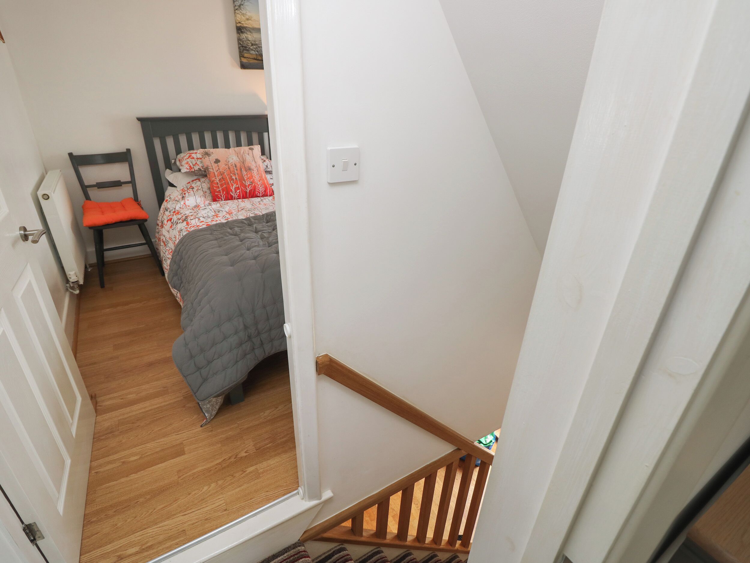 A bedroom with a bed, a chair, and a radiator.