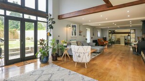 A spacious living area with a large sliding glass door leading to a backyard, a grey sofa, a white armchair, and a wooden dining table.