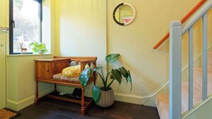 A room with a wooden bench, a potted plant, a mirror, and a staircase. - Kent Downs Cottage (Canterbury)