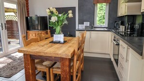 Una cocina moderna con una mesa de comedor de madera, armarios blancos y un horno empotrado.