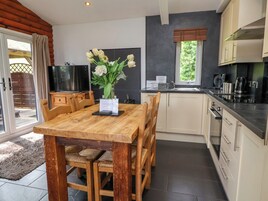 Una cocina moderna con una mesa de comedor de madera, armarios blancos y un horno empotrado.