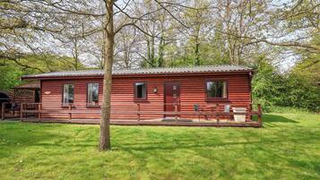 A red log cabin with a porch and a small table and chair set.