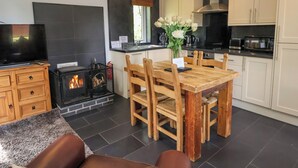 Una cocina moderna con armarios blancos, una mesa de comedor con sillas, una chimenea y un televisor.