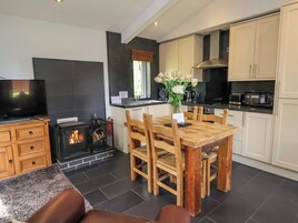 Una cocina moderna con armarios blancos, una mesa de comedor con sillas, una chimenea y un televisor.