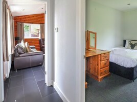 Un dormitorio con un aparador de madera, una cama con almohada de cabeza de ciervo, y un baño con banco de madera y toallero.