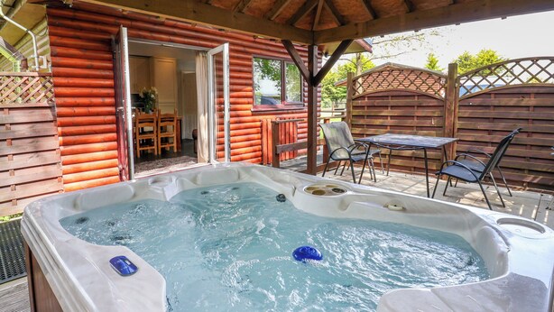 Un jacuzzi en una cabaña de madera con zona de terraza.