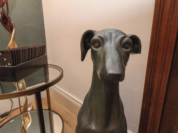 A sculpture of a dog in a room with a mirror and a small table.
