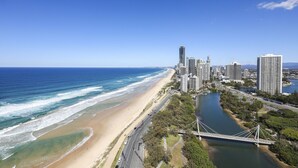 A coastal cityscape with a beach, a river, and a bridge.