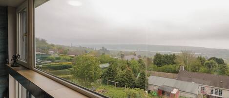 A view from a window overlooking a residential area with houses, greenery, and a distant landscape.