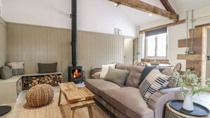 A cozy living room with a wooden ceiling, a sofa, a coffee table, and a fireplace. - Alder Cottage - Fold Yards (Matlock)
