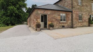 A stone building with a gravel driveway and a large tree to the left. - Alder Cottage - Fold Yards (Matlock)