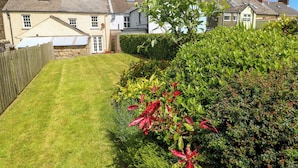 A well-maintained garden with a lawn, various shrubs, and a wooden fence. - Orielton Cottage (Newport)
