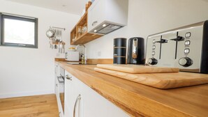 Eine moderne Küche mit Holzarbeitsplatten, einer Kaffeemaschine und einem eingebauten Backofen.