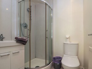 A bathroom with a glass-enclosed shower, a white toilet, and a sink with a towel.