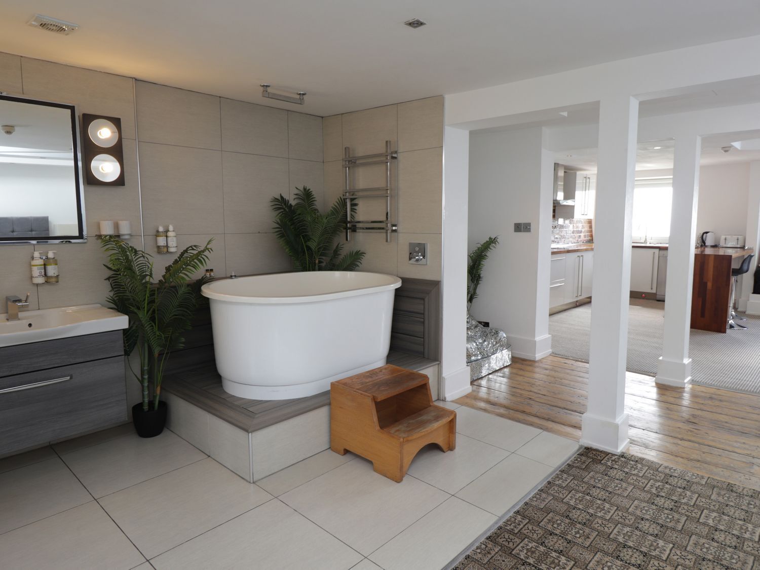Ein modernes Badezimmer mit einer freistehenden Badewanne, einem Waschtisch mit Spiegel und Topfpflanzen.
