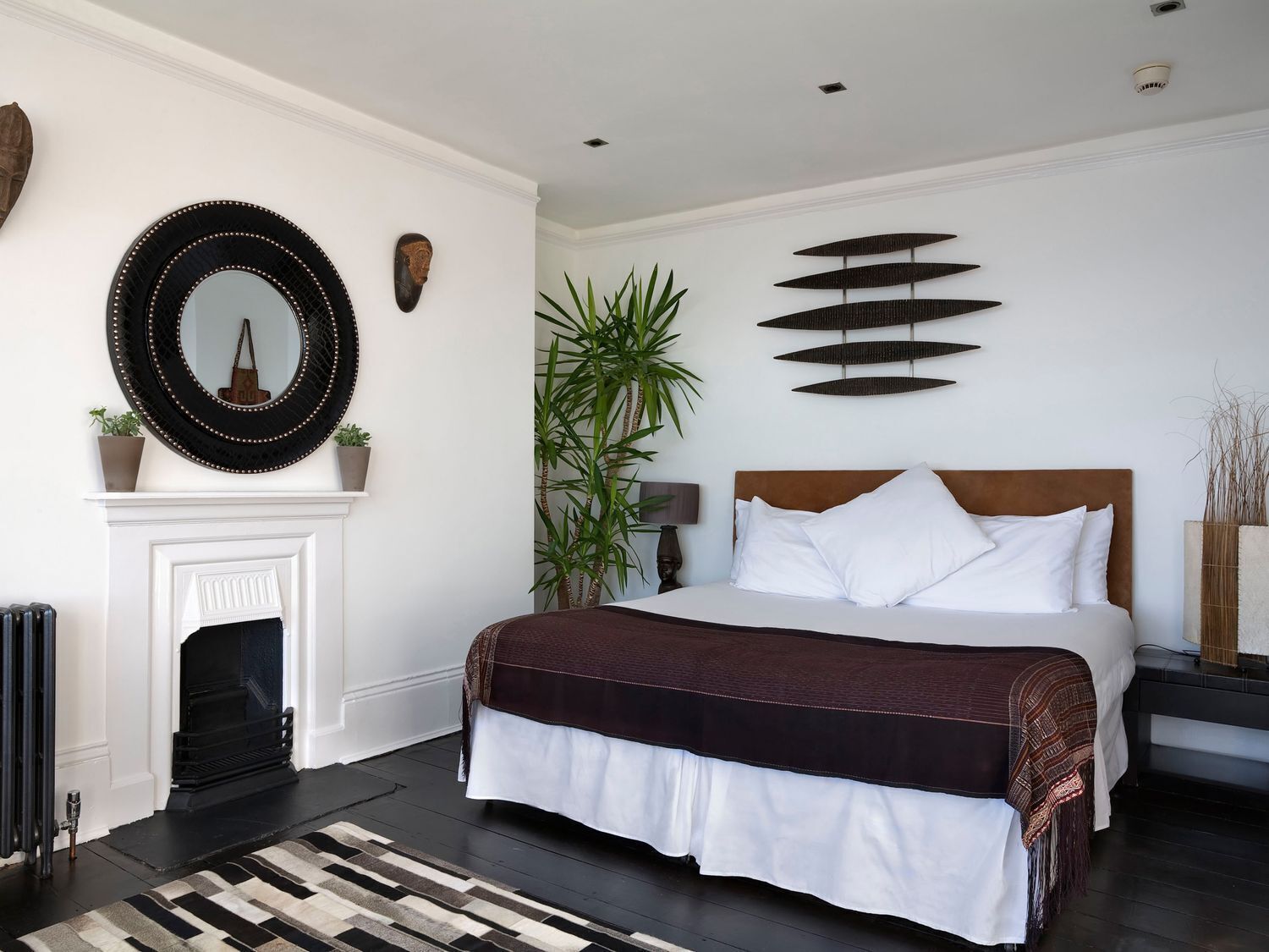 Un dormitorio moderno con una cama grande, una chimenea y decoración en la pared.