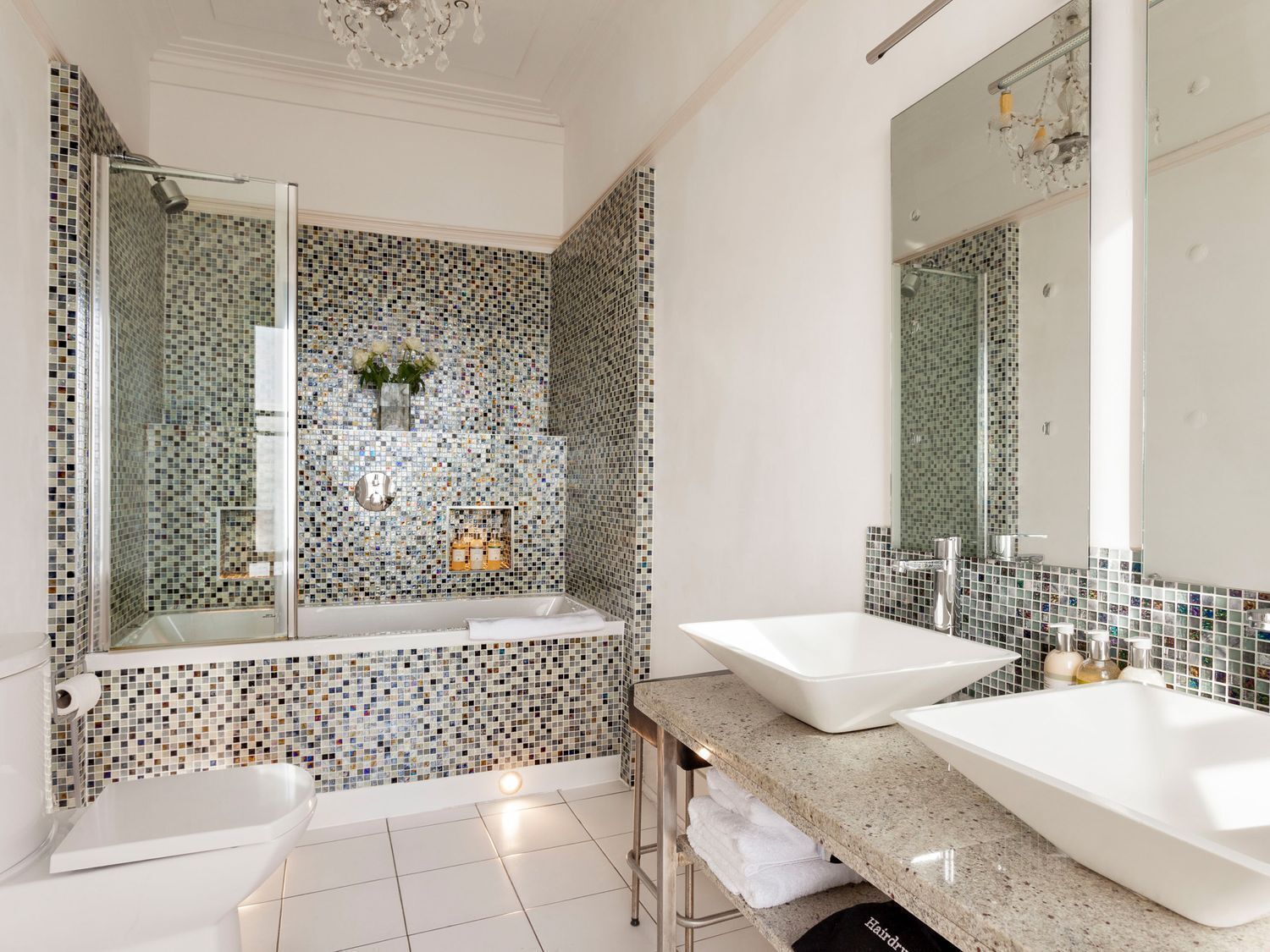 A modern bathroom with two sinks, a bathtub, and a shower.