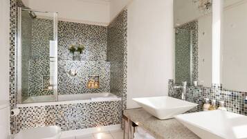A modern bathroom with two sinks, a bathtub, and a shower.