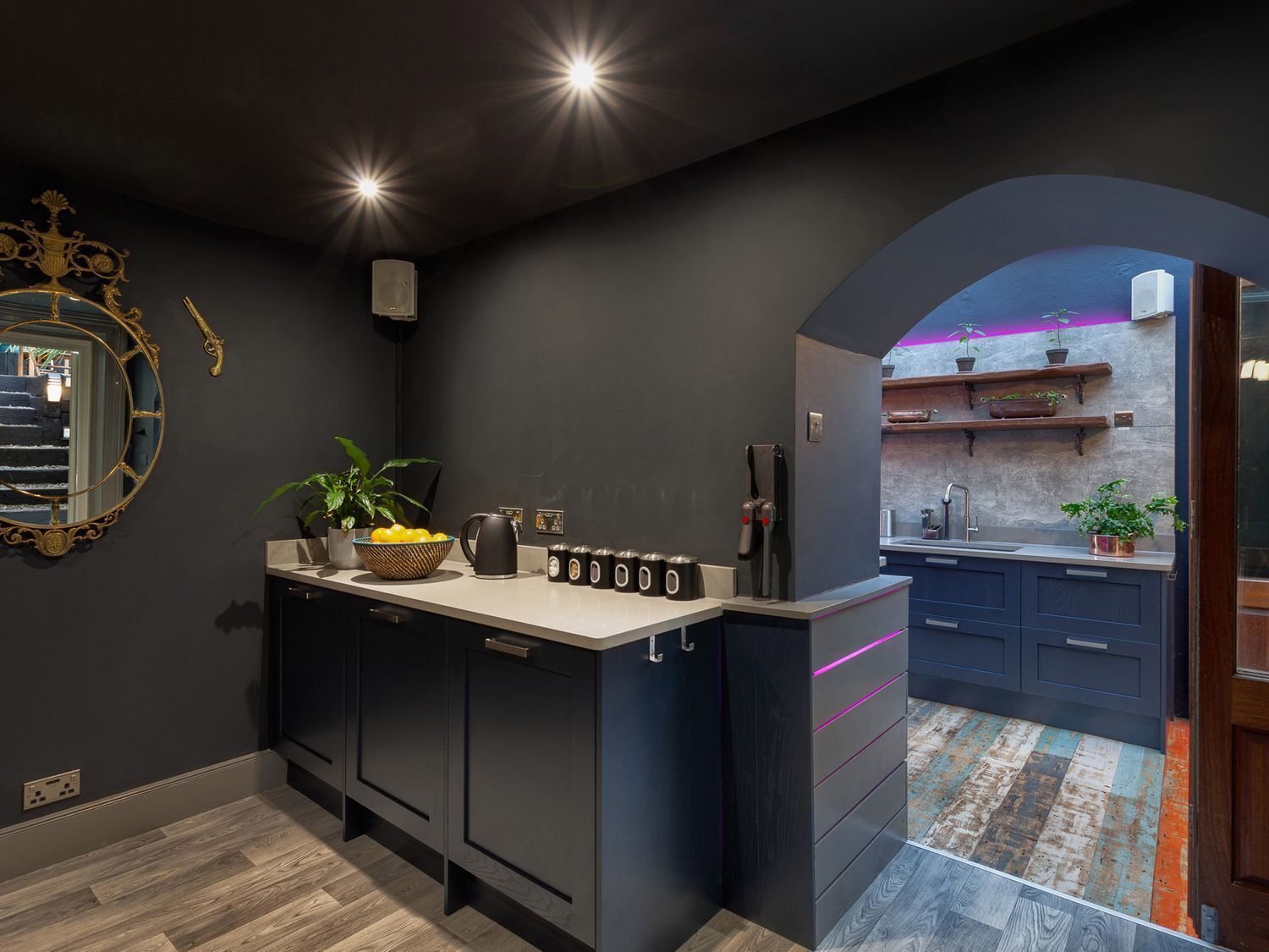 A modern kitchen with dark cabinetry, a central island, and a view into an adjacent room.