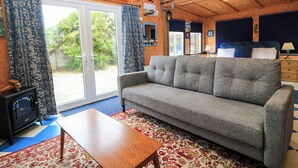 A cozy living room with a grey sofa, a wooden coffee table, and a patterned rug. - The Games Room (Chichester)