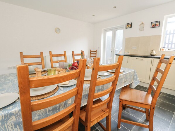 A dining area with a table set for six, surrounded by wooden chairs. - Dotties Retreat (Weymouth)
