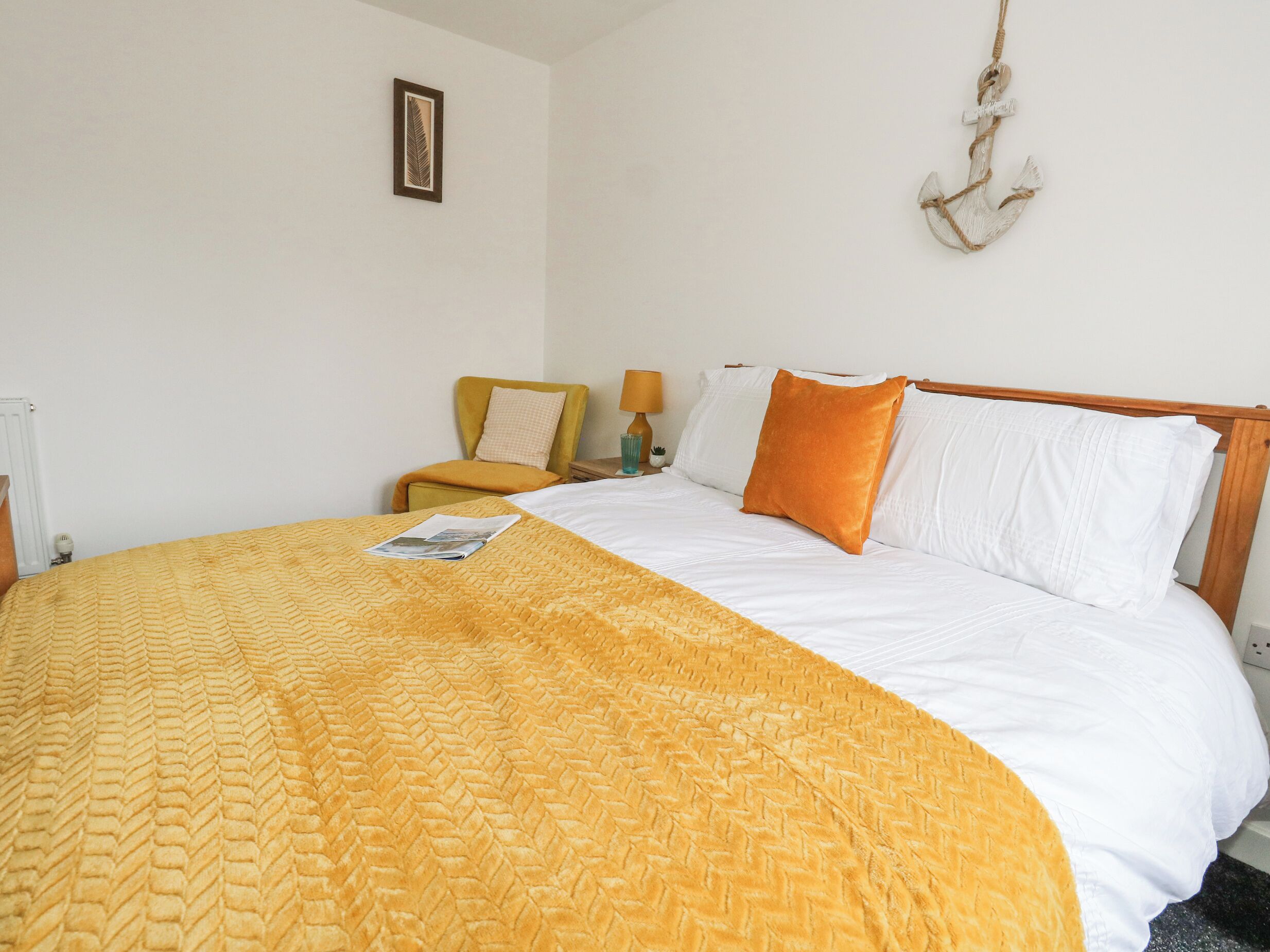 A neatly made bed with a yellow blanket, white pillows, and a wooden headboard.