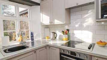 A modern kitchen with white cabinets, a stainless steel sink, and a built-in oven.
