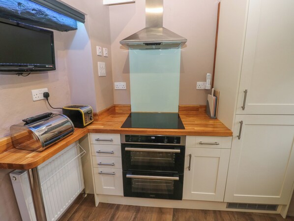 A compact kitchen with a built-in oven, a toaster, and a microwave.