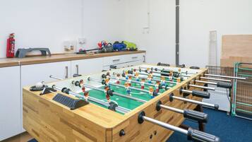 A foosball table in a room with a blue carpet, wooden cabinets, and a fire extinguisher on the wall.