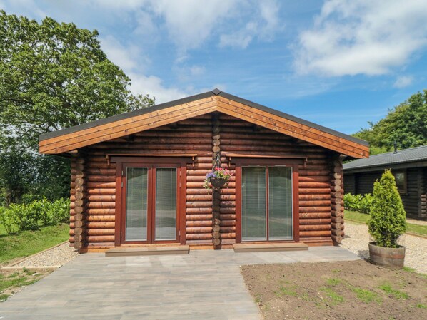 A log cabin with a wooden exterior, two large sliding glass doors, and a small porch area. - Carlton Lodge 1 (Middlesbrough)