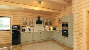 L’intérieur d’une cabane en rondins comprend un coin cuisine, un plancher en bois et un tapis beige.