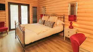 Une chambre située dans une cabane en rondins, avec un lit, une table de chevet et une chaise.