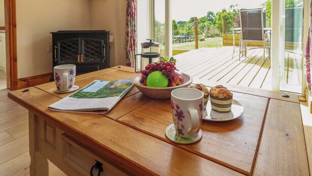 Une table en bois sur laquelle se trouvent un livre, un bol de fruits, une tasse et une assiette avec une théière.