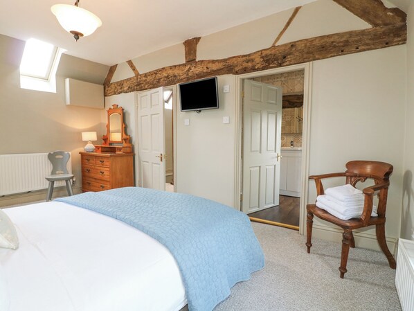 A bedroom with a bed, dresser, chair, and a television on the wall. - The Creamery (Burton on Trent)
