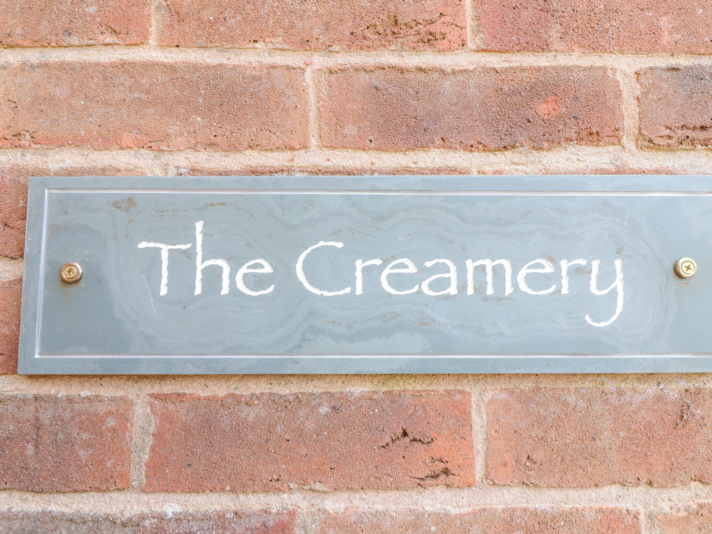 A sign on a brick wall that reads "The Creamery."
