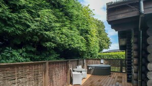 Een houten terras met rieten meubels en een jacuzzi.
