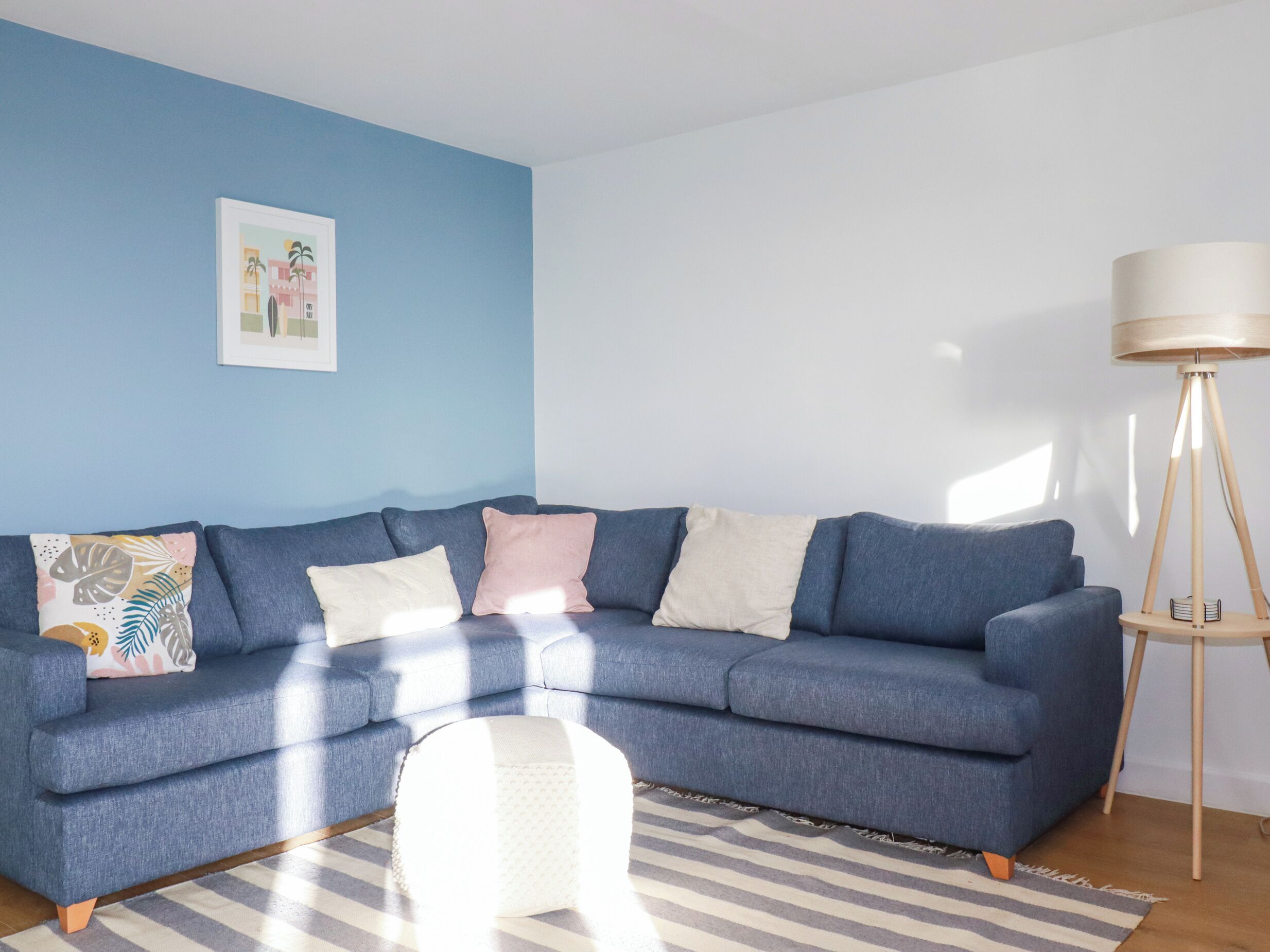 Un salón con un sofá azul, una lámpara de pie y un tapete a rayas.