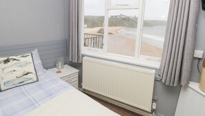 A bedroom with a large window, a bed, a dresser, and a radiator. - Apartment 4 (Tenby)