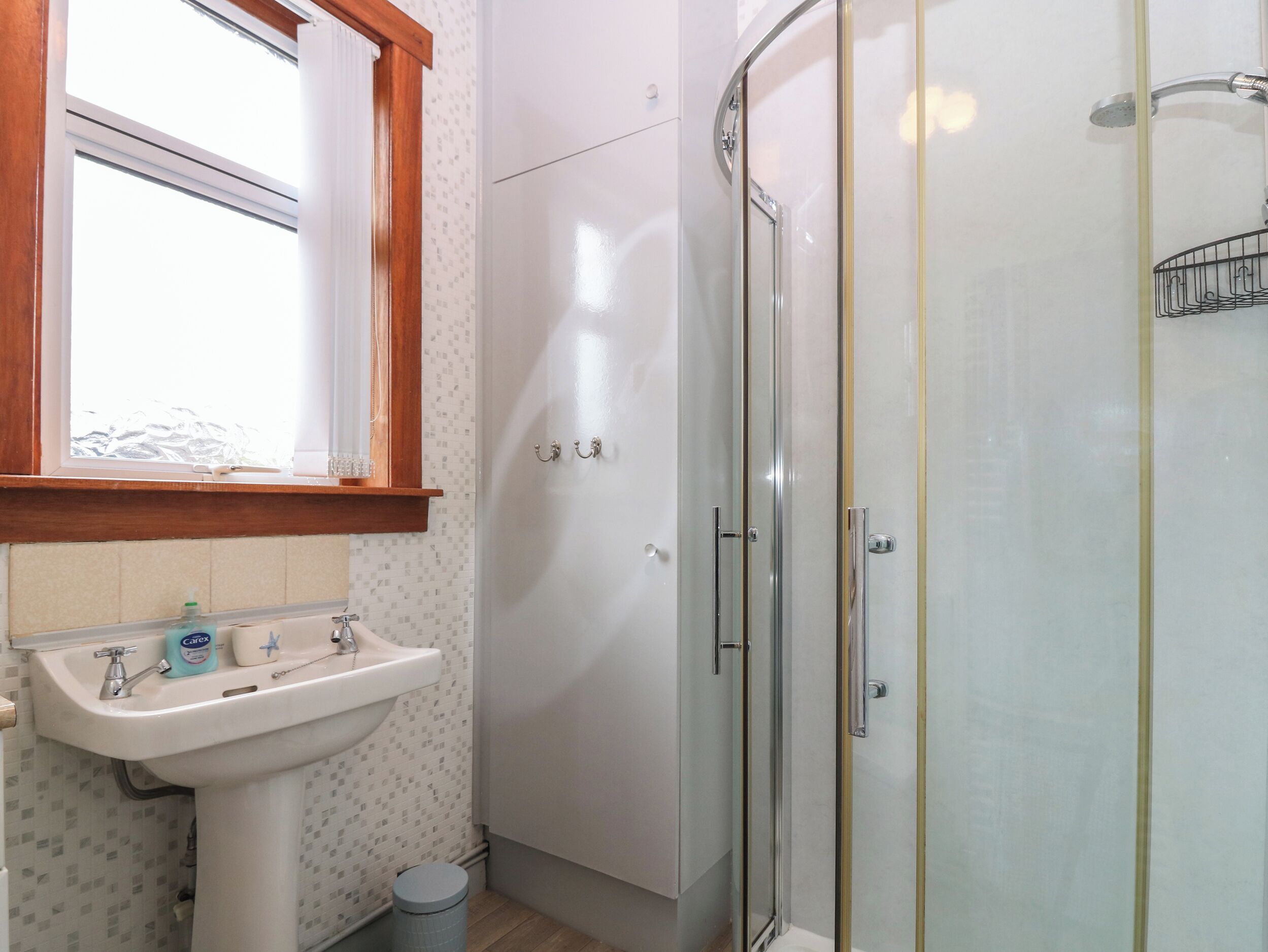 A bathroom with a sink, mirror, and shower.