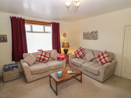 A living room with two beige sofas, a wooden coffee table, and a lamp.