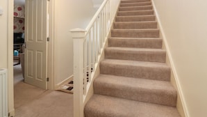 A carpeted staircase with white railings leading to a landing. - Thain House (Banff)