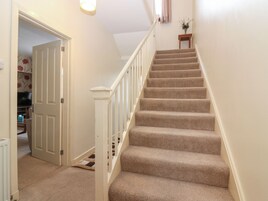 A carpeted staircase with white railings leading to a landing.