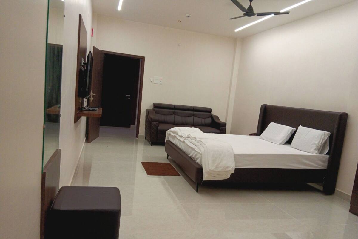 Une chambre à coucher avec un lit, un canapé, une petite table et un ventilateur de plafond.