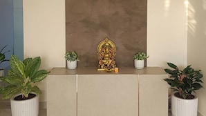 A reception desk with a brown backdrop, potted plants on either side, and a golden statue in the center.