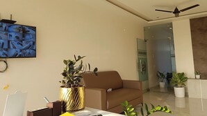 A modern living room with a sofa, a coffee table, and a TV mounted on the wall displaying multiple camera feeds.
